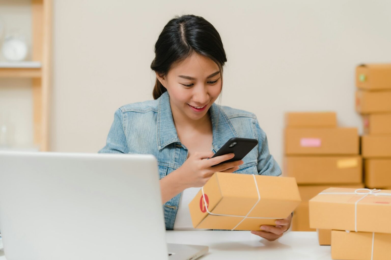 Online store owner packing orders next to a laptop